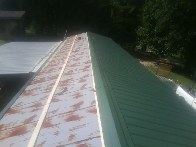 Old rusted panels beside newly installed green metal roofing — Wind Damage Roof Repair by Roofing Brothers in Lenexa