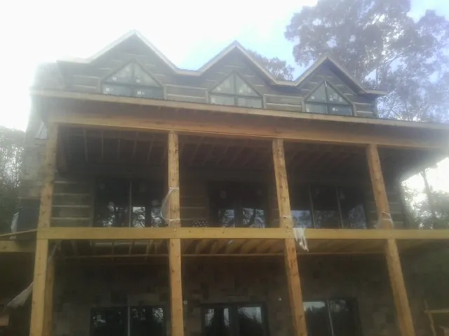 Dormers and porch framing on a large log home under construction — Roof Coating work by our crew in Lenexa