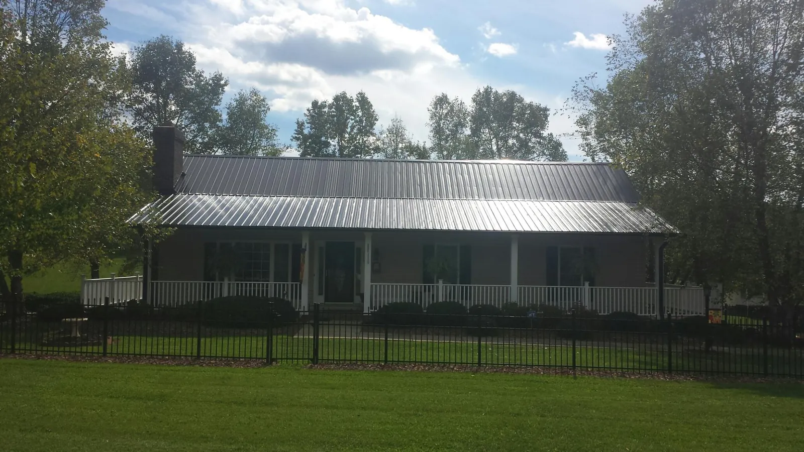 Gray metal roof on a brick ranch with a full width front porch — Gutter Guard Installation work by our crew in Lenexa
