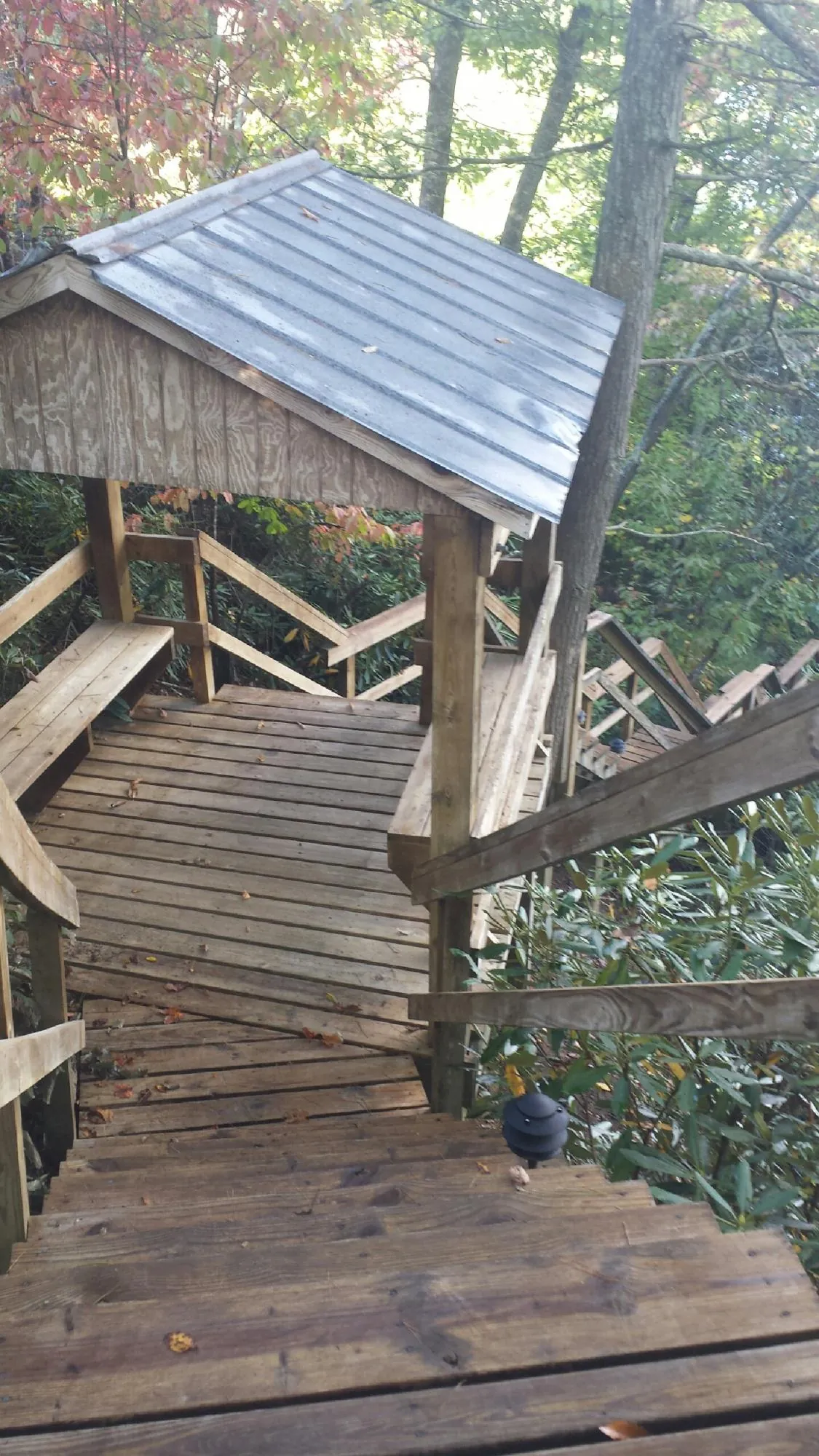 Metal roofed shelter over wooden steps on a wooded walkway — Skylight Repair & Installation work by our crew in Lenexa
