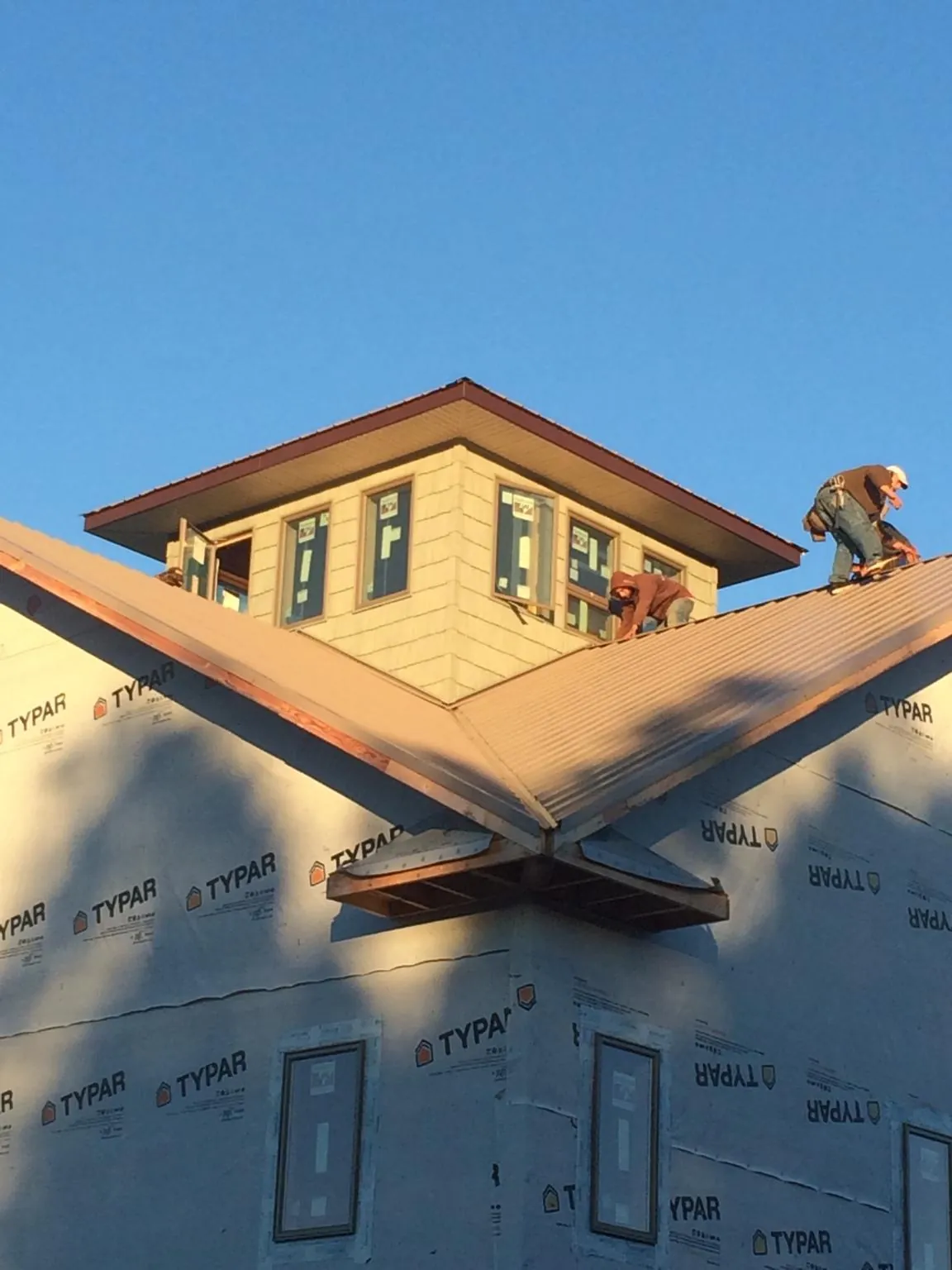 Roofers working around a rooftop cupola on a new metal roof at sunset — Roof Waterproofing in Lenexa by Roofing Brothers